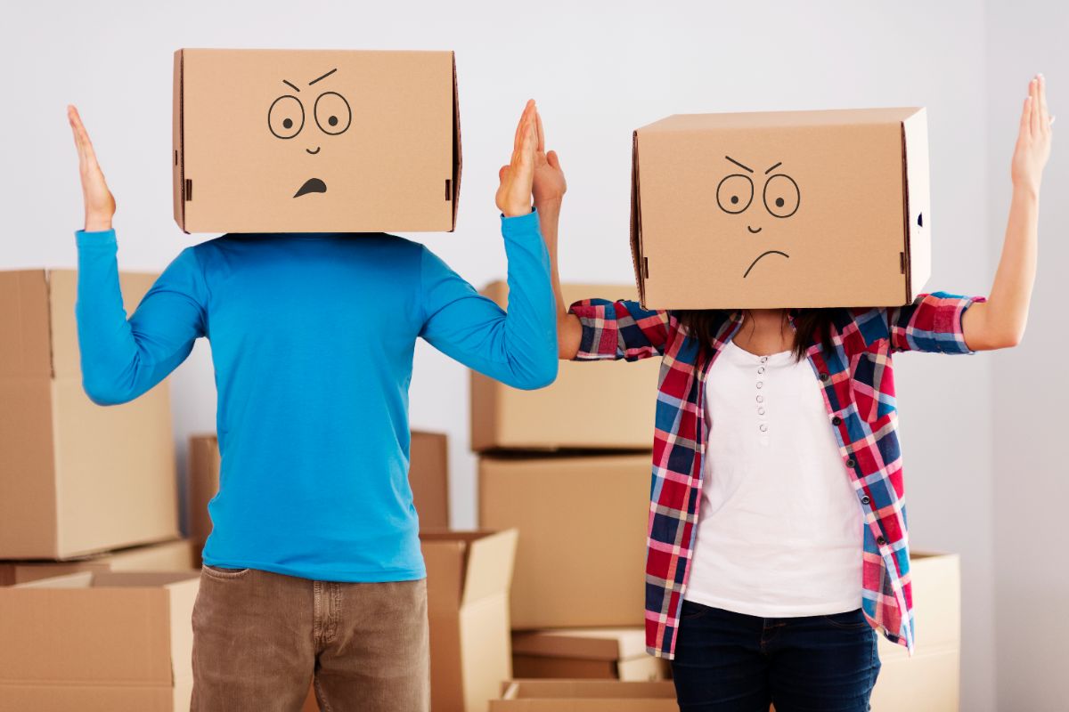 two people with cardboard boxes on their heads surrounded by moving boxes representing common self storage mistakes